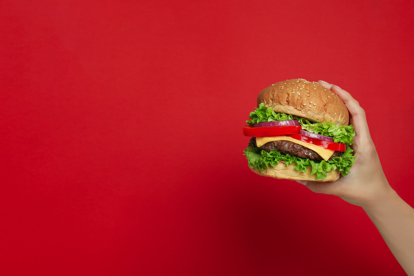 Concept of Tasty Food with Burger on Red Background